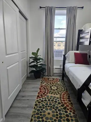 a bedroom with a bed and a rug next to a window at 20 minutes to Central Park Manhattan New York City 16 mins Metlife stadium in West New York