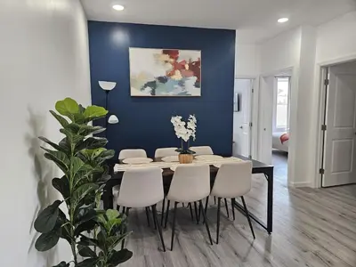 a dining room table with white chairs and a blue wall at 20 minutes to Central Park Manhattan New York City 16 mins Metlife stadium in West New York
