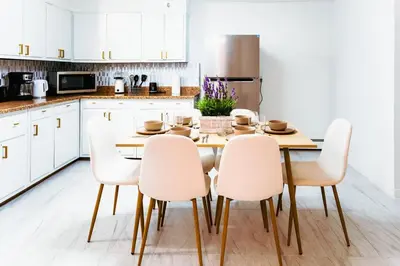a kitchen with a wooden table and white chairs at Fast transit to Manhattan with Parking on premises in North Bergen