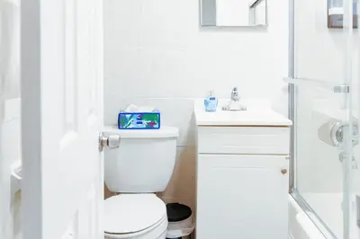 a white bathroom with a toilet and a shower at Fast transit to Manhattan with Parking on premises in North Bergen