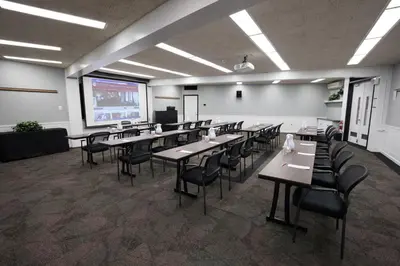 a classroom with tables and chairs and a projection screen at Rutgers University Inn and Conference Center in New Brunswick