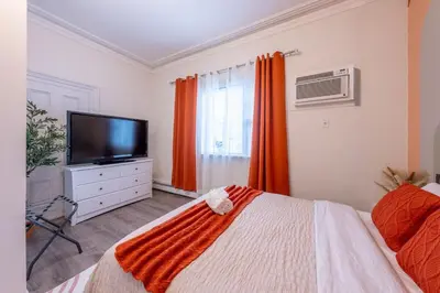 a bedroom with a flat screen tv and a bed at 5BR 3BTH House, Steps to Bars, Dining, NYC Access with GameRm, Backyard with BBQ and Parking in Jersey City