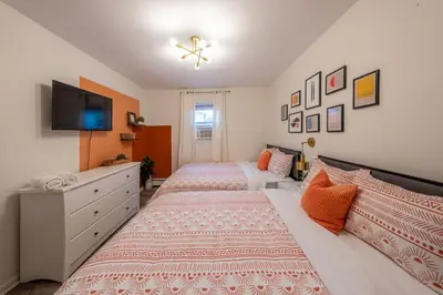 a bedroom with two beds and a tv on the wall at 5BR 3BTH House, Steps to Bars, Dining, NYC Access with GameRm, Backyard with BBQ and Parking in Jersey City