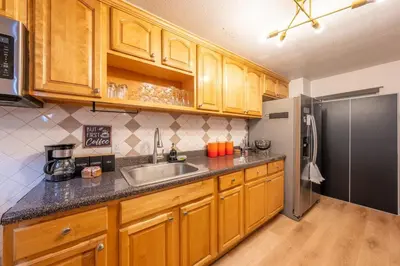 a kitchen with wooden cabinets and a stainless steel refrigerator at 5BR 3BTH House, Steps to Bars, Dining, NYC Access with GameRm, Backyard with BBQ and Parking in Jersey City