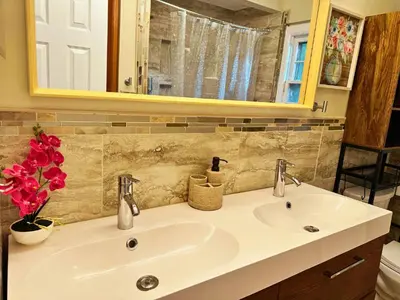 a bathroom with a sink and a mirror and flowers at Cozy Riverside View House in Montague
