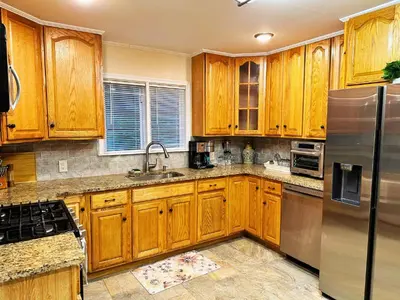 a kitchen with wooden cabinets and a stainless steel refrigerator at Cozy Riverside View House in Montague