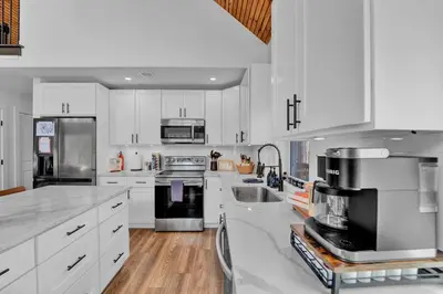 a large white kitchen with white cabinets and appliances at Chalet with Hot Tub, Game, Movie Room, Lake and Pool Access in Gouldsboro