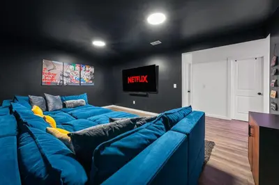 a living room with a blue couch and a tv at Chalet with Hot Tub, Game, Movie Room, Lake and Pool Access in Gouldsboro