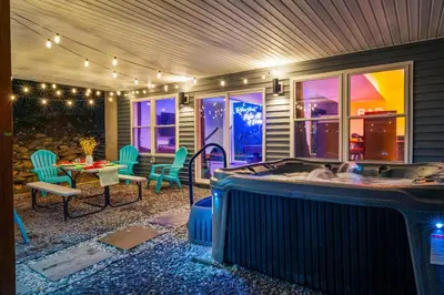 a hot tub on a patio with a table and chairs at Chalet with Hot Tub, Game, Movie Room, Lake and Pool Access in Gouldsboro