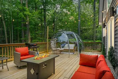 a patio with a couch and a fireplace on a deck at Chalet with Hot Tub, Game, Movie Room, Lake and Pool Access in Gouldsboro
