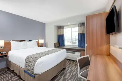 a hotel room with a bed and a flat screen tv at Microtel Inn & Suites by Wyndham Philadelphia Airport Ridley Park in Ridley Park