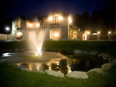 a house with a fountain in front of a yard at night at Stroudsmoor Country Inn in Stroudsburg