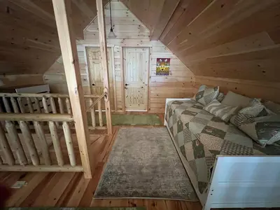 a room with a bed and a staircase in a cabin at Luxury Cabin with Outdoor HotTub-NEW Construction in Lake Ariel