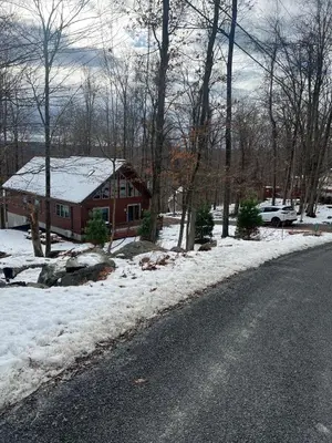 a house with snow on the ground next to a road at Luxury Cabin with Outdoor HotTub-NEW Construction in Lake Ariel