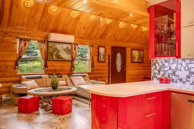 a kitchen and living room with red cabinets and a couch at Stunning! Pocono Escape! HotTub Sauna Pool Ski Pet-Friendly Firepit Game Room Fireplace BBQ Lakes Tennis Fishing in Long Pond