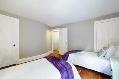 two beds in a room with white walls and wooden floors at Spacious Broadway Home Downtown Western Modern Charm with parking in Jim Thorpe
