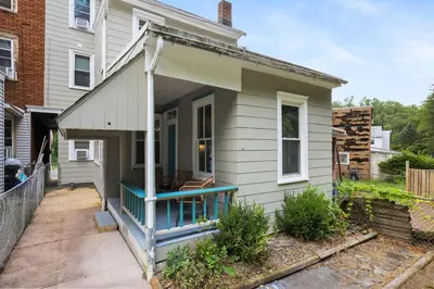 a small white house with a porch with a chair at Spacious Broadway Home Downtown Western Modern Charm with parking in Jim Thorpe