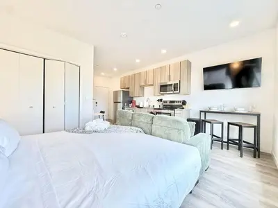 a bedroom with a large white bed and a kitchen at Studio Apt with Skyline Views, King Bed, and Gym in Philadelphia