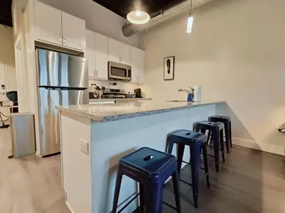 a kitchen with a counter with stools and a refrigerator at Cozy Philly Studio with Free Parking for Long Term Stays in Philadelphia