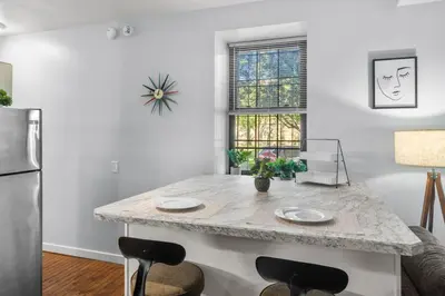 a kitchen with a counter with two chairs and a refrigerator at Quaint and Stylish APT with King Bed for Long Term Stay in Philadelphia