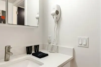 a white bathroom with a blow dryer on a sink at Chic Apartment with King Bed in Old City in Philadelphia