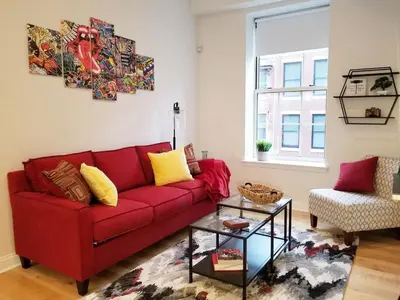 a red couch in a living room with a table at Old City Apartment with Full Kitchen in Philadelphia