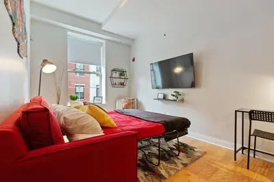 a living room with a red couch and a flat screen tv at Old City Apartment with Full Kitchen in Philadelphia
