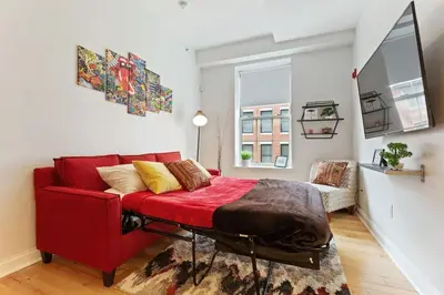 a red bed in a room with a red couch at Old City Apartment with Full Kitchen in Philadelphia
