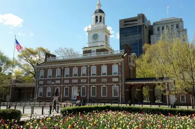a building with a clock tower on top of it with flowers at Old City Apartment with Full Kitchen in Philadelphia