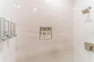 a white bathroom with a shower with white tiles at Downtown Philly 1BR with Stunning Views in Philadelphia
