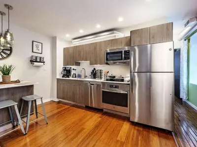 a kitchen with a stainless steel refrigerator and wooden cabinets at Tasteful 1 Bedroom Apt in Historic Old City in Philadelphia