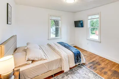 a bedroom with a large bed and two windows at York Farmhouse Hideaway Near Lake Redman in York
