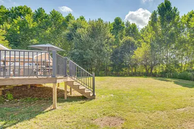a wooden deck with an umbrella on a field at York Farmhouse Hideaway Near Lake Redman in York