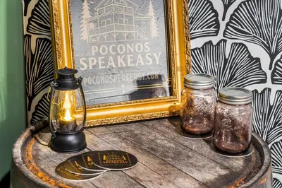 a table with two glass jars on a barrel with a picture at Pocono Speak Easy Hot Tub Golf Simulator 1920 Bar in East Stroudsburg