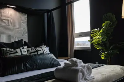a bedroom with a bed with black pillows and a window at Luxe 1br- Free Parking-King Bed in East Orange