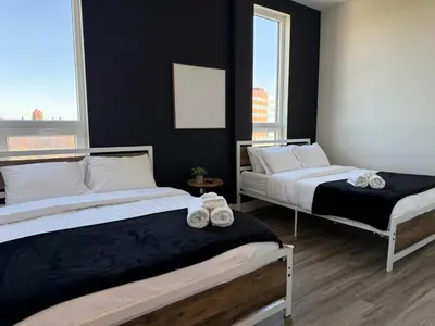 two beds in a room with black walls and windows at NYC View, Free Parking, 2bath in East Orange