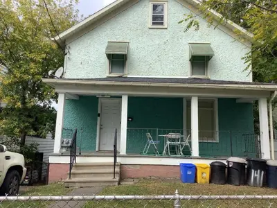 a blue house with a table on the porch at Relaxing, Spacious Private Room near Binghamton in Johnson City