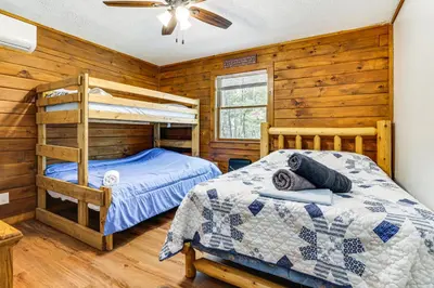 a bedroom with two bunk beds and a ceiling fan at Long Pond Log Cabin with Hot Tub Soaks and Outdoor Fun in Long Pond