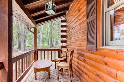 a porch with two chairs and a table and a window at Long Pond Log Cabin with Hot Tub Soaks and Outdoor Fun in Long Pond