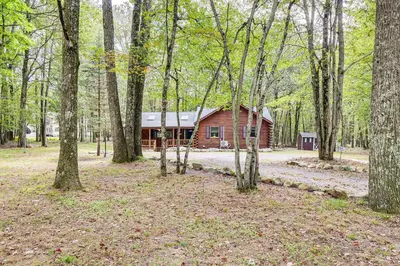 a log cabin in the middle of a forest at Long Pond Log Cabin with Hot Tub Soaks and Outdoor Fun in Long Pond
