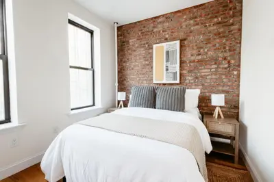 a bedroom with a brick wall and a bed at Spacious 3BR Upper West Side Apt - Steps from Central Park in New York