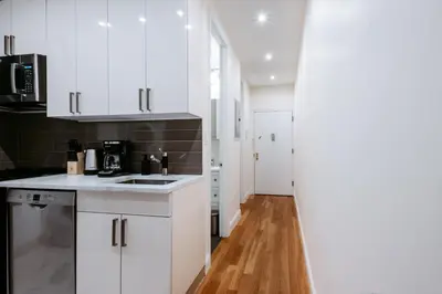 a kitchen with white cabinets and a wooden floor at Spacious 3BR Upper West Side Apt - Steps from Central Park in New York
