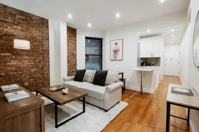 a living room with a couch and a brick wall at Spacious 3BR Upper West Side Apt - Steps from Central Park in New York