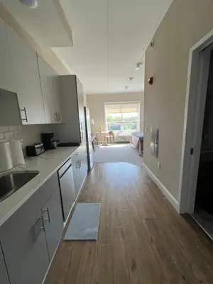 a kitchen with white cabinets and a wooden floor at 410 Modern Brand New Studio Apartment in Old Bridge