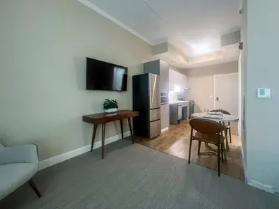 a living room with a kitchen with a table and a refrigerator at 408 Modern Brand New Studio Apartment in Old Bridge