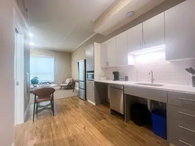 a kitchen with white cabinets and a table and a chair at 408 Modern Brand New Studio Apartment in Old Bridge