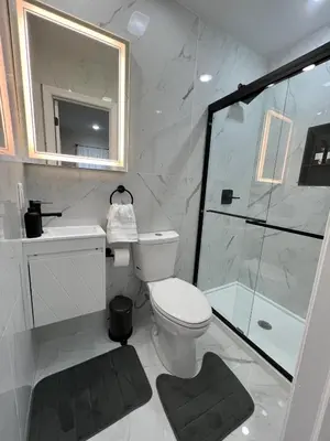 a white bathroom with a toilet and a shower at Modern 2BR and Office Near NYC With Parking - Sleeps 6 in Jersey City