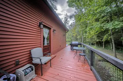 a wooden deck with chairs and a grill on the side of a house at Willow Brook Getaway Hot Tub, Deck in Mifflinburg in Mifflinburg