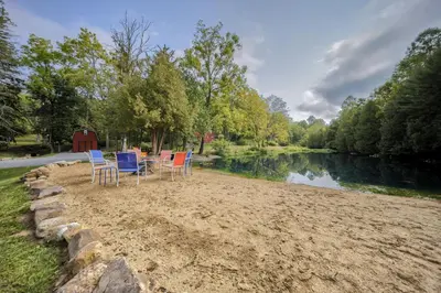 a group of chairs sitting on the sand next to a river at Willow Brook Getaway Hot Tub, Deck in Mifflinburg in Mifflinburg