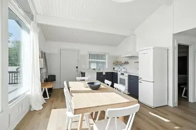 a white kitchen with a wooden table and white appliances at Lakelyn Lodge in Lakeville